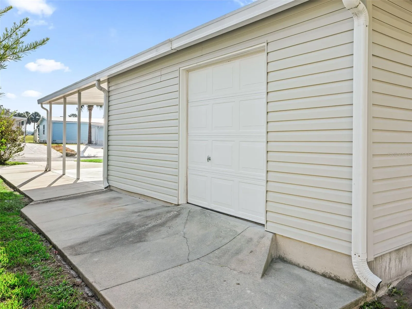 EXTERIOR of GOLF CART GARAGE in rear of home - Note concrete path on N side of home and GUTTERS &amp; DOWNSPOUTS.