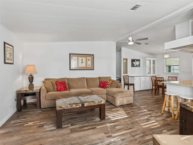 Another view of LIVING ROOM - Shows CATHEDRAL CEILING from a different angle, HALLWAY to bedrooms (center back), DINING ROOM (back R), and KITCHEN BREAKFAST BAR (far R).