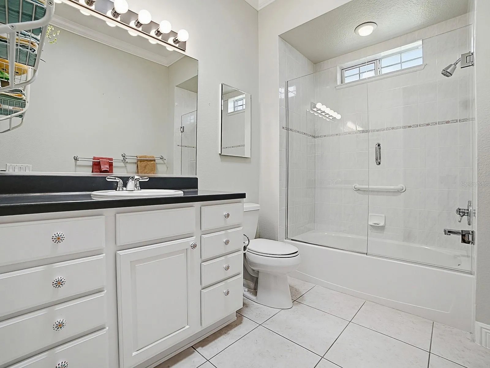 THE GUEST BATHROOM HAS A FRAMELESS GLASS ENCLOSURE ON THE TUB/SHOWER.