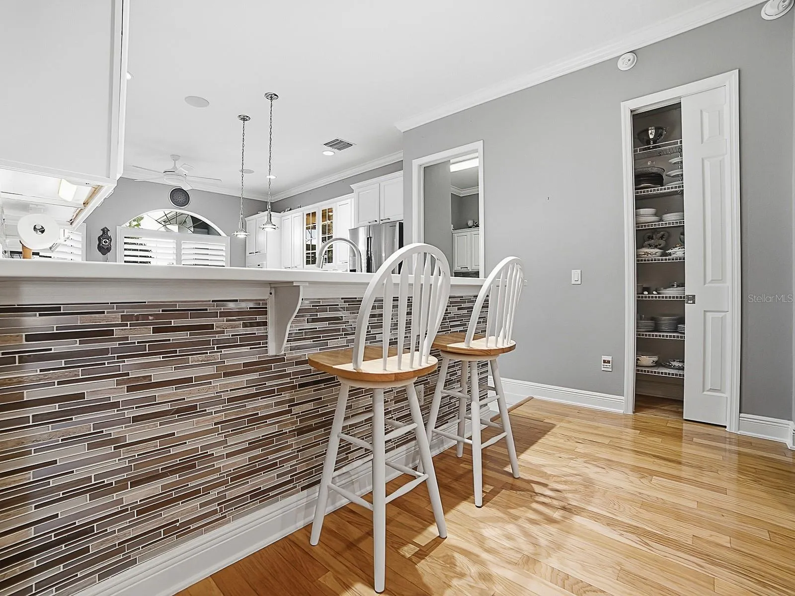 THE FRONT OF THE BREAKFAST BAR IS FINISHED OFF NICELY WITH THE SAME TILE AS THE BACKSPLASH. A CUSTOM CLOSET PANTRY WAS ALSO ADDED. THE DOOR TO THE LEFT OF THE PANTRY LEADS TO THE LAUNDRY ROOM.