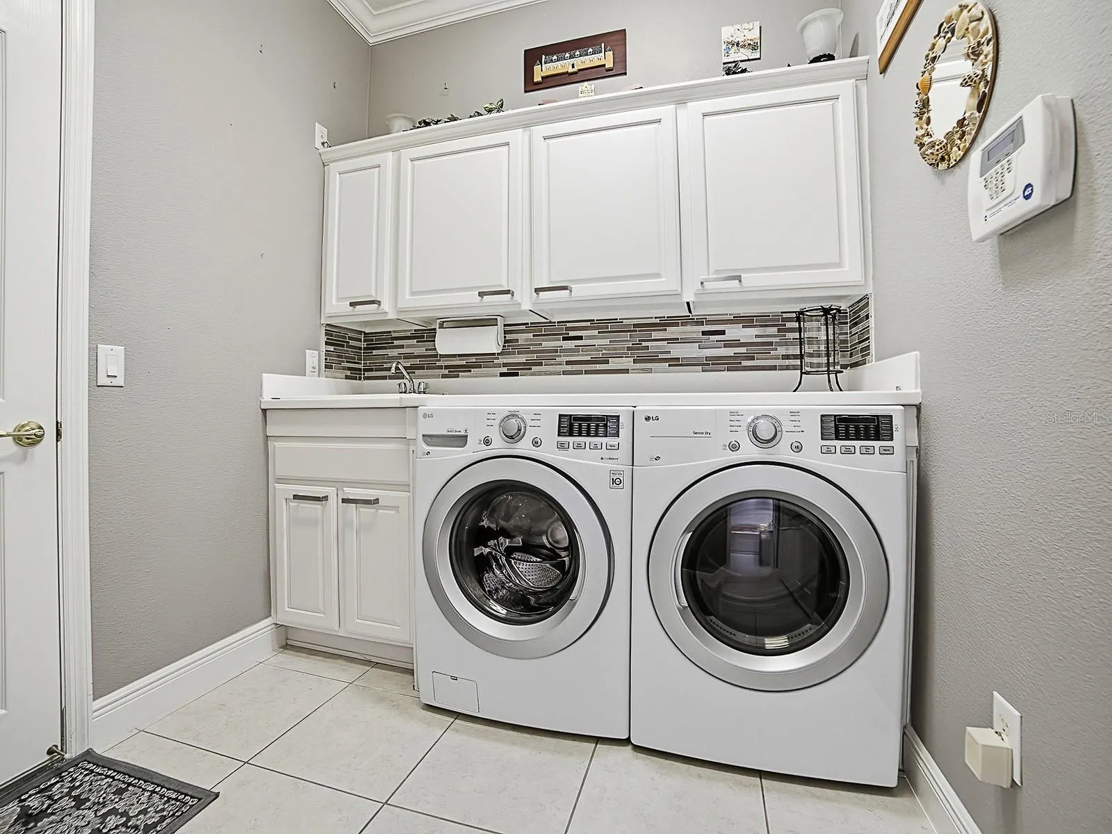 EXPANDED LAUNDRY ROOM OFFERS THE SAME LOVELY DETAILS AS THE KITCHEN WITH FRONT LOAD WASHER AND DRYER.