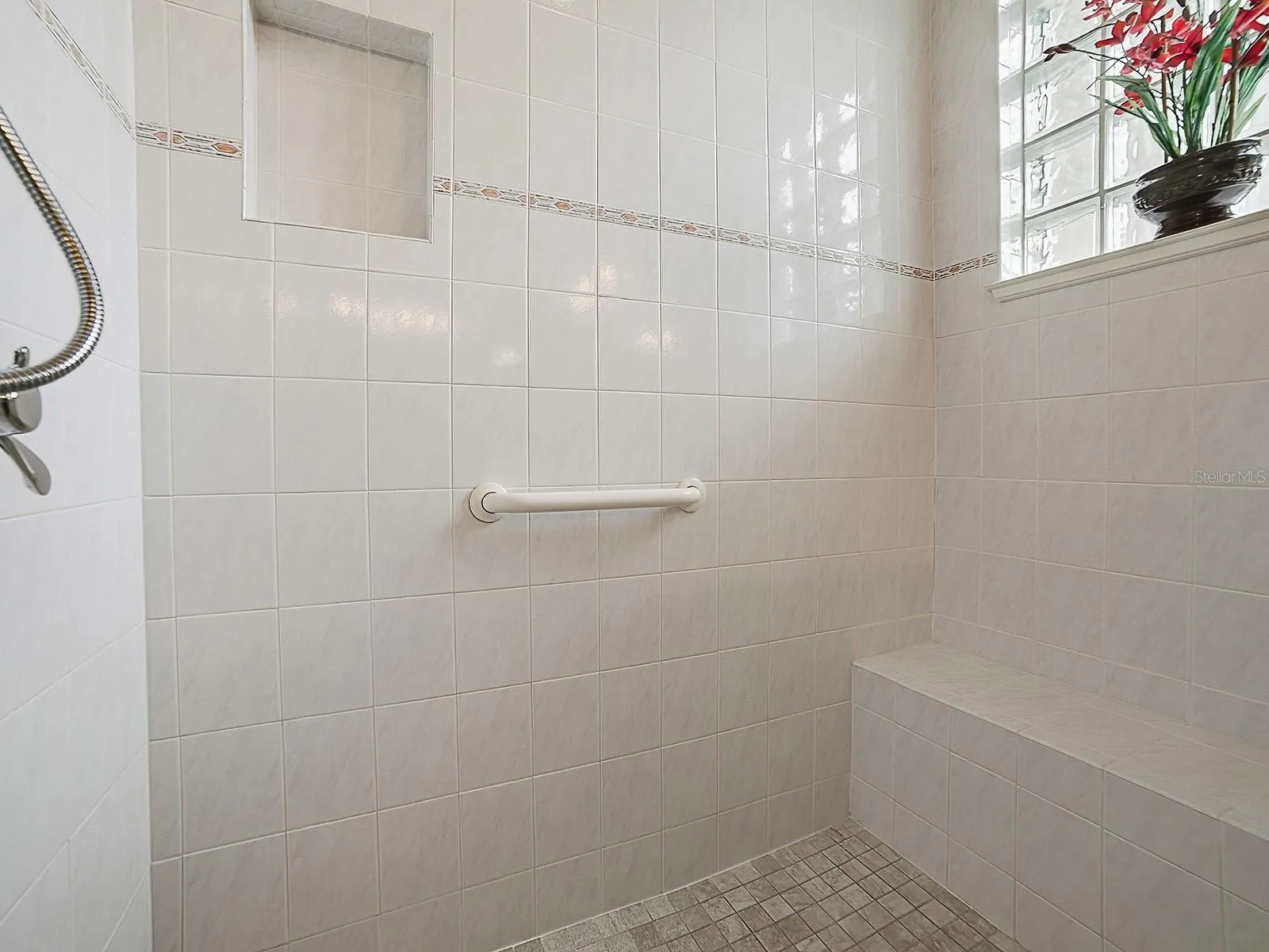 SPACIOUS TILED SHOWER WITH A BENCH.