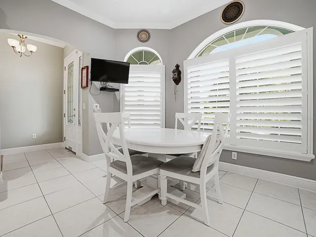 TO THE LEFT AS YOU ENTER THE HOME, YOU'LL FIND THE CUSTOM KITCHEN WITH A CASUAL DINING NOOK, PLANTATION SHUTTERS, AND WALL MOUNTED TV.