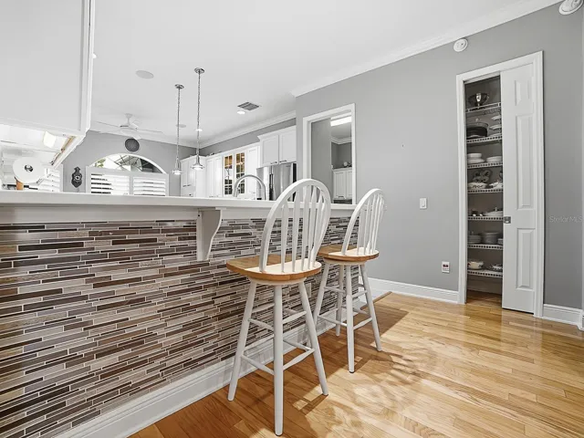 THE FRONT OF THE BREAKFAST BAR IS FINISHED OFF NICELY WITH THE SAME TILE AS THE BACKSPLASH. A CUSTOM CLOSET PANTRY WAS ALSO ADDED. THE DOOR TO THE LEFT OF THE PANTRY LEADS TO THE LAUNDRY ROOM.