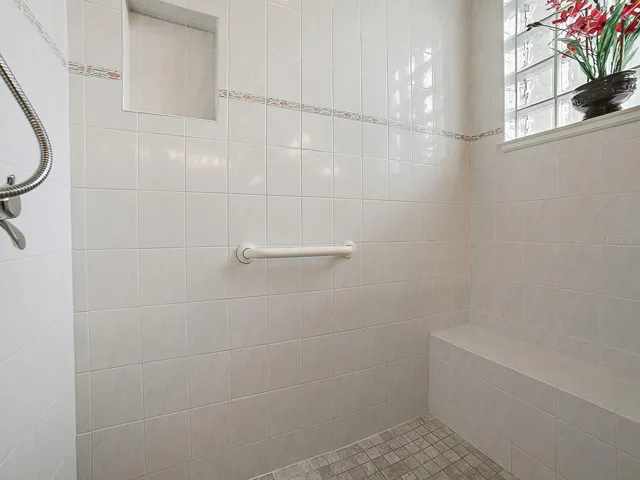 SPACIOUS TILED SHOWER WITH A BENCH.