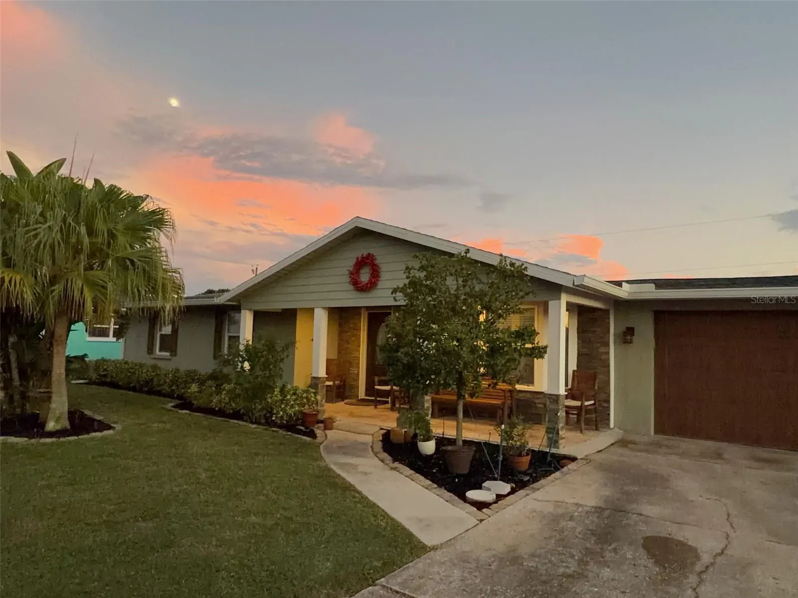 Twilight view of the covered front porch featuring warm lighting and a seating area at 412 Redwood Road, Venice, Florida