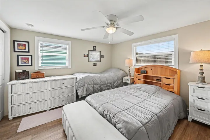 Comfortable primary bedroom featuring a ceiling fan, two windows, and ample space for multiple beds at 412 Redwood Road, Venice, Florida