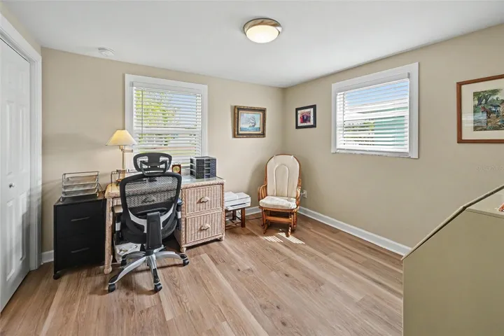 Bedroom currently utilized as a bright home office with two windows and wood-look flooring at 412 Redwood Road, Venice, Florida