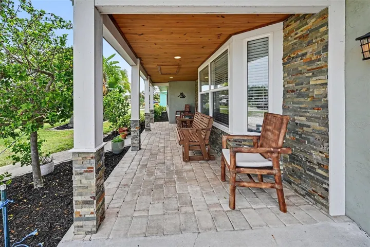 Covered front porch featuring a wood ceiling and brick pavers at 412 Redwood Road, Venice, Florida