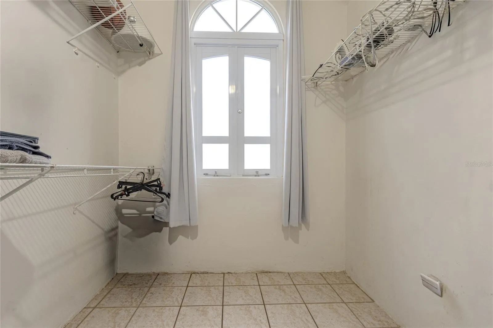 Walk-in closet with arched window and shelving / Walk-in closet con ventana de arco y tablillas Walk-in closet with arched window and shelving / Walk-in closet con ventana de arco y tablillas