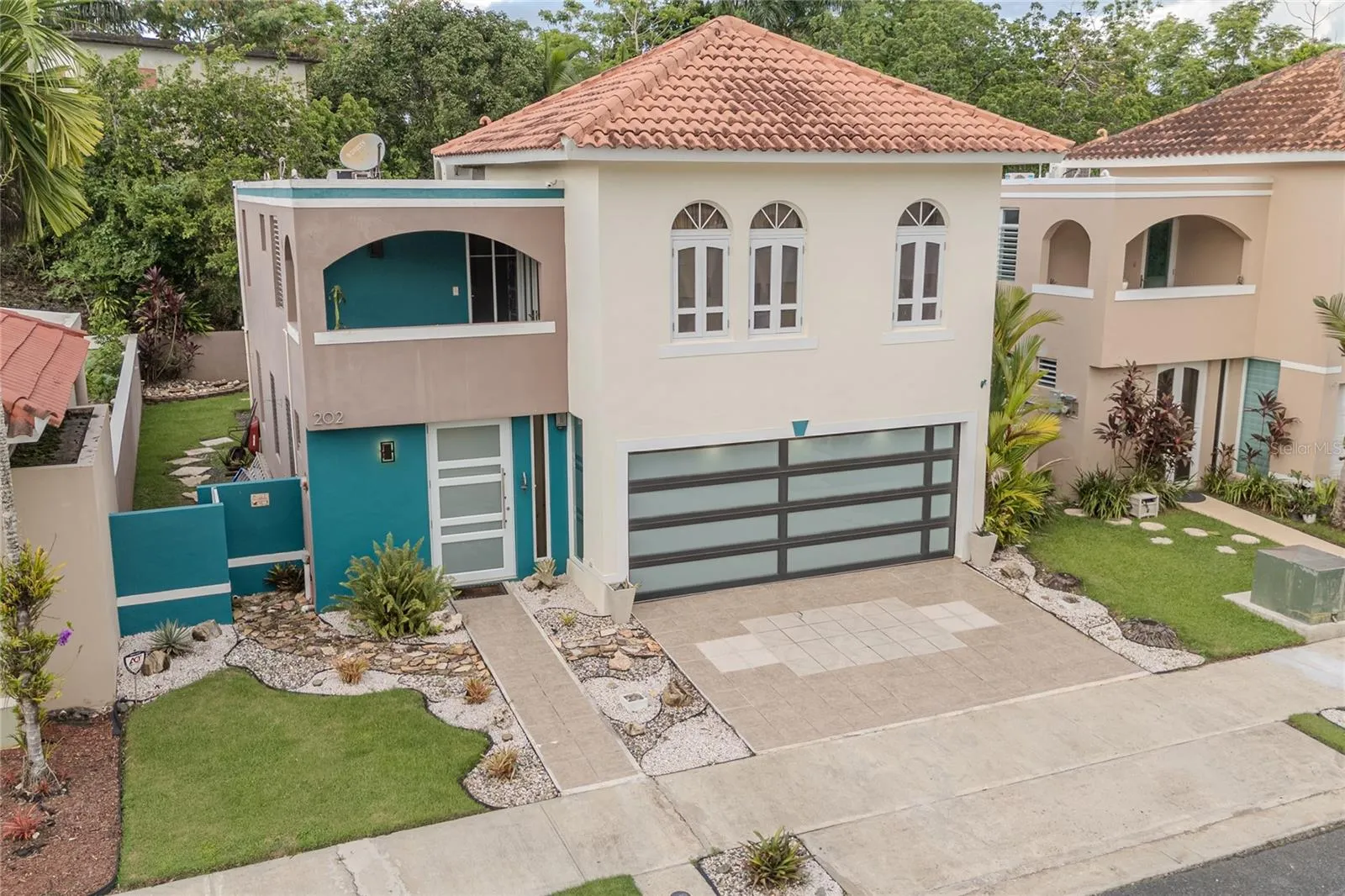Aerial front view with landscaped yard and tile roof / Vista aérea frontal con jardinería y techo de tejas Aerial front view with landscaped yard and tile roof / Vista aérea frontal con jardinería y techo de tejas