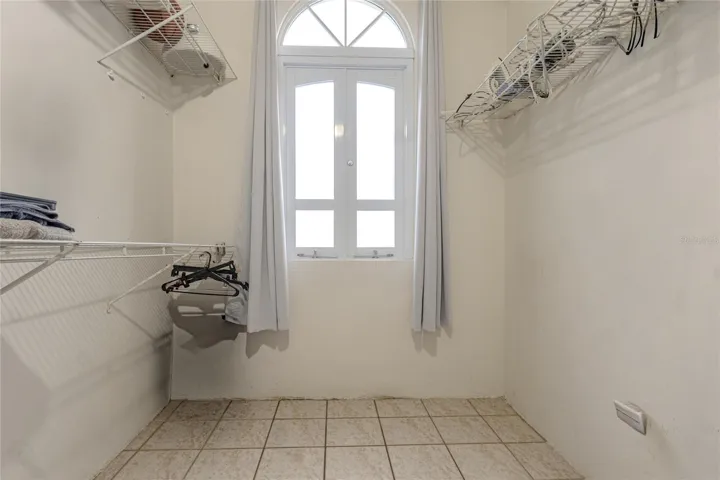 Walk-in closet with arched window and shelving / Walk-in closet con ventana de arco y tablillas
