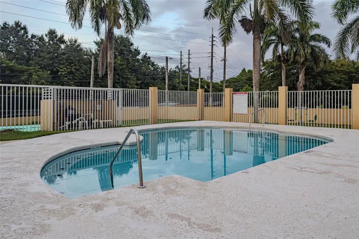 Community pool surrounded by palm trees / Piscina comunal rodeada de palmas