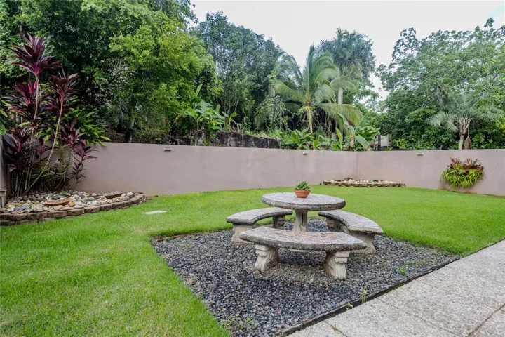 Fenced backyard with lawn and stone picnic set / Patio cercado con grama y juego de picnic en piedra
