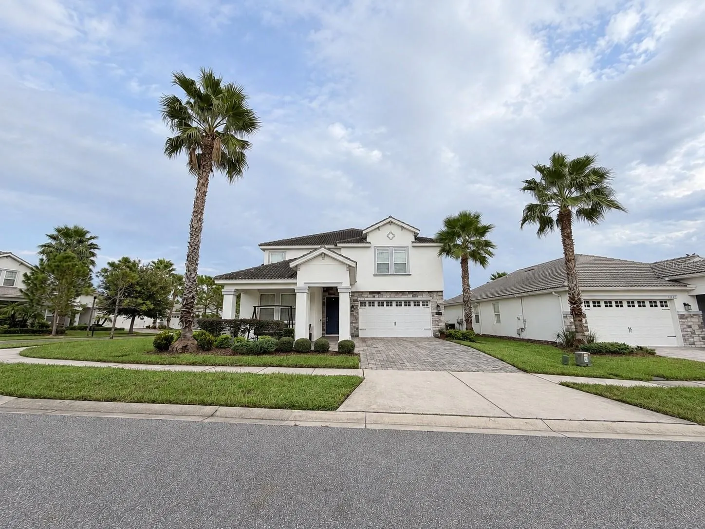 Beautiful curb appeal with mature palm trees, manicured landscaping and a welcoming covered entry.