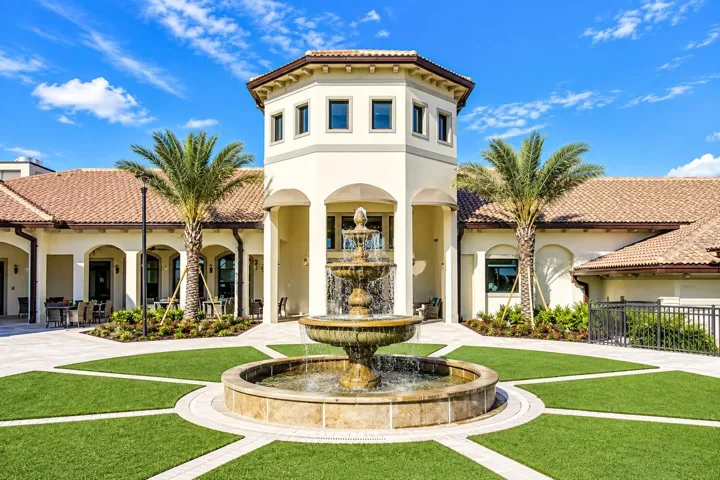 Elegant ChampionsGate clubhouse entrance featuring Mediterranean-inspired architecture, tropical landscaping and a central fountain.