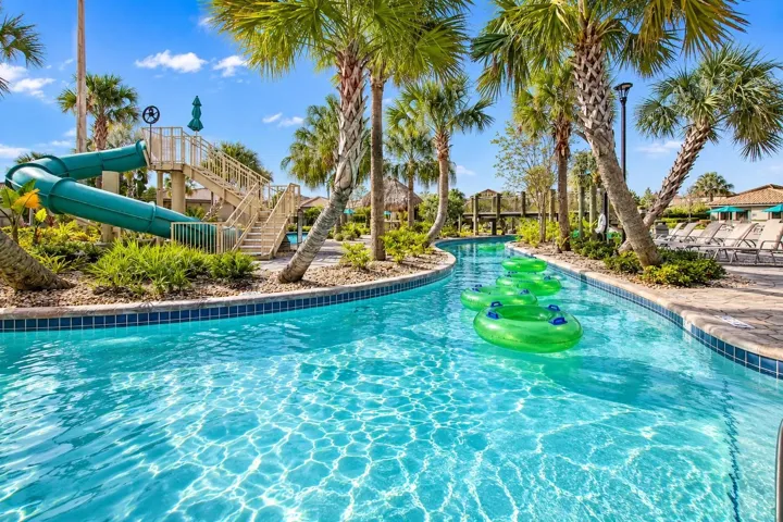 Resort-style lazy river surrounded by tropical landscaping, lounge areas and water attractions.