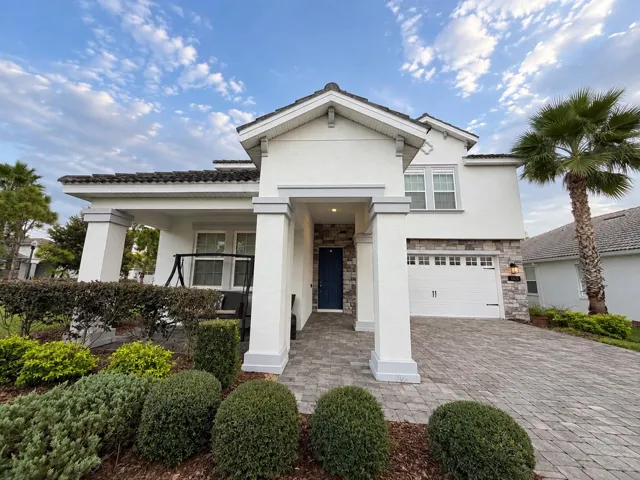 Inviting front elevation featuring a covered porch, stone accents and paver driveway.