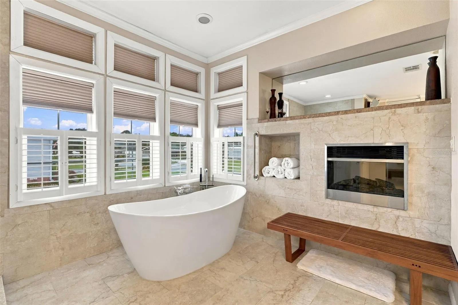 Huge ensuite bath w/plantation shutters, freestanding soaking tub, and electric fireplace.