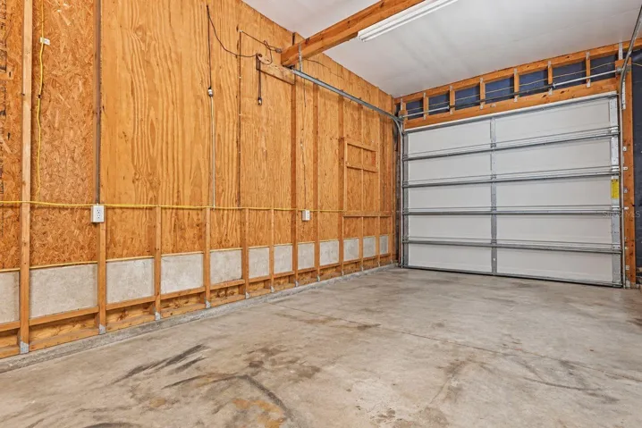 Virtually altered photo of the interior of the garage/workshop w/AC unit and two garage door openings.