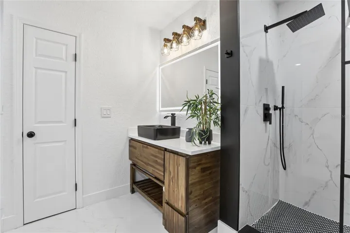 Designer primary bath with vessel sink, illuminated mirror and modern finishes