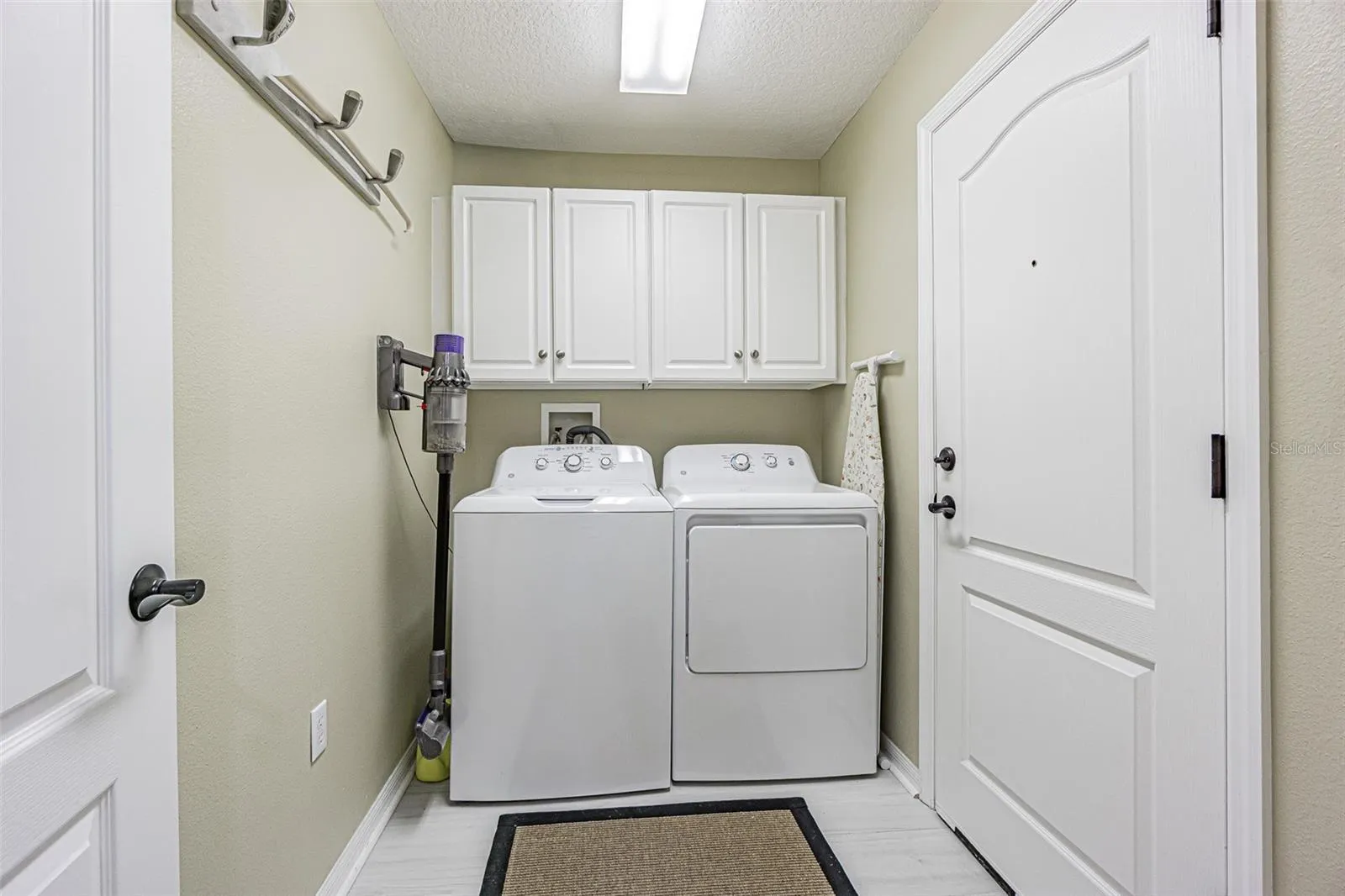 Interior laundry room with storage cabinets above