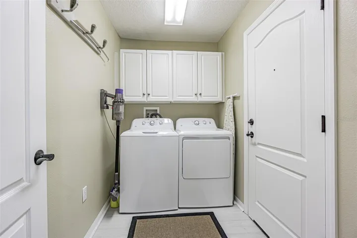 Interior laundry room with storage cabinets above
