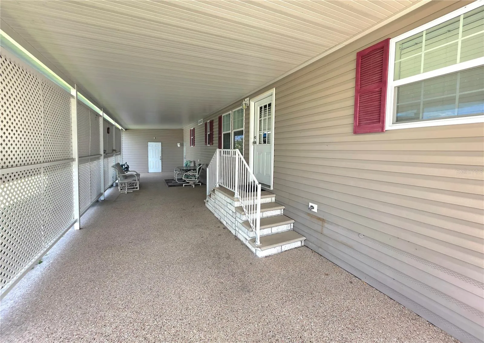 Long carport with privacy lattice, shade awnings &amp; main entry door to Kitchen.