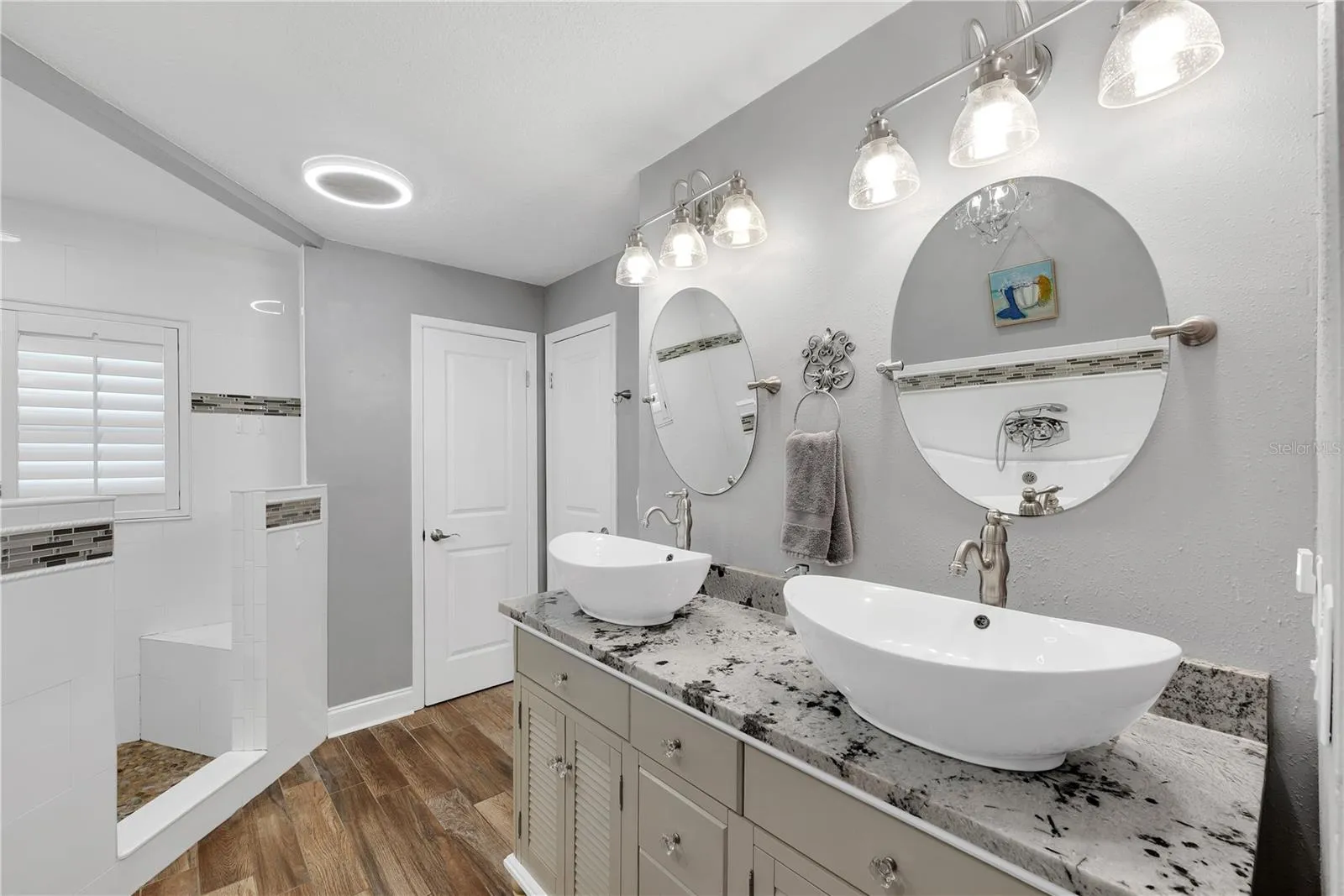 The primary bathroom has a large corner shower with multiple showerheads and built-in bench, dual sinks, linen closet storage and private water closet.