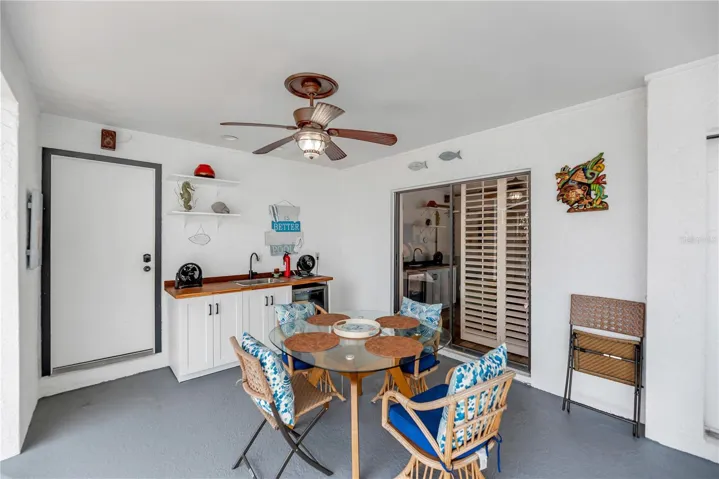 The back porch just off the primary suite has a build-in storage closet for pool toys and outdoor cushions and a serving station with sink and refrigerator for entertaining and outdoor grilling.