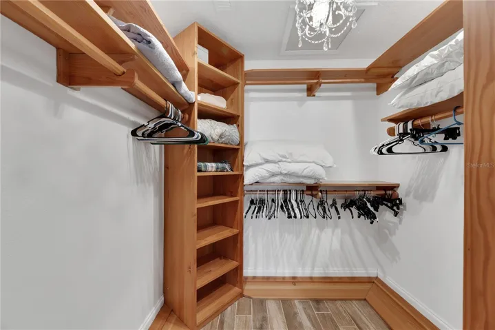 Spacious walk-in closet with custom built shelves and shoe storage.