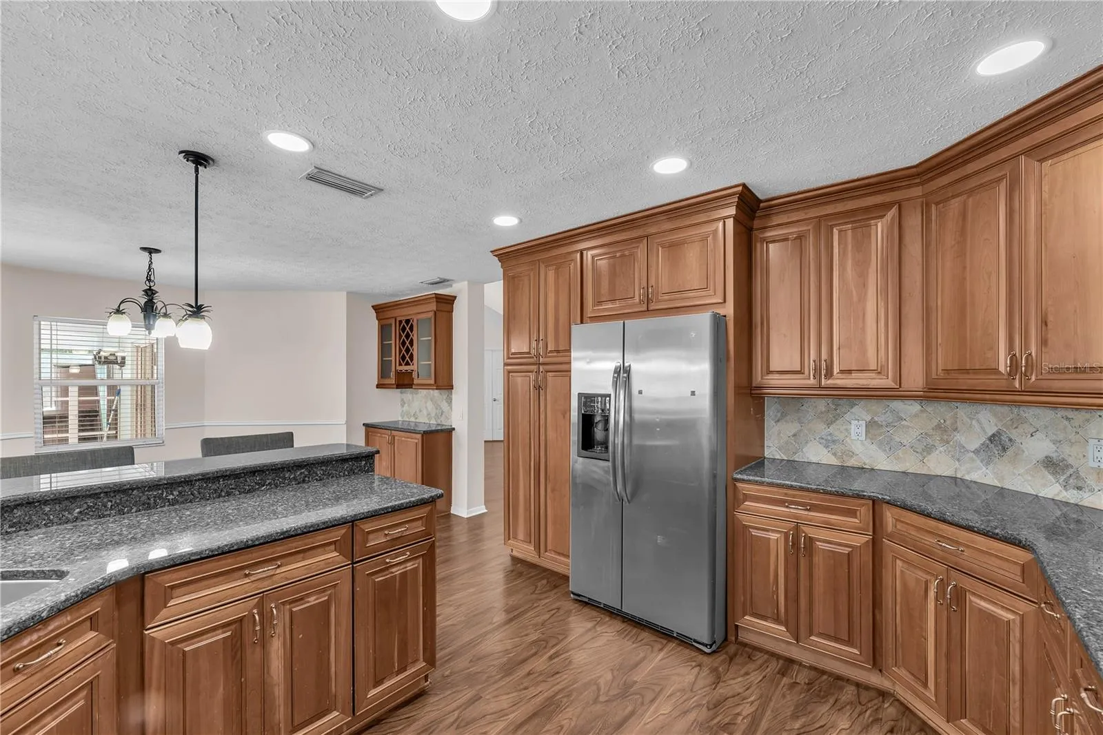 At the heart of the home, the spacious kitchen features custom wood cabinetry, Level 5 granite countertops, stone backsplash and stainless steel appliances.