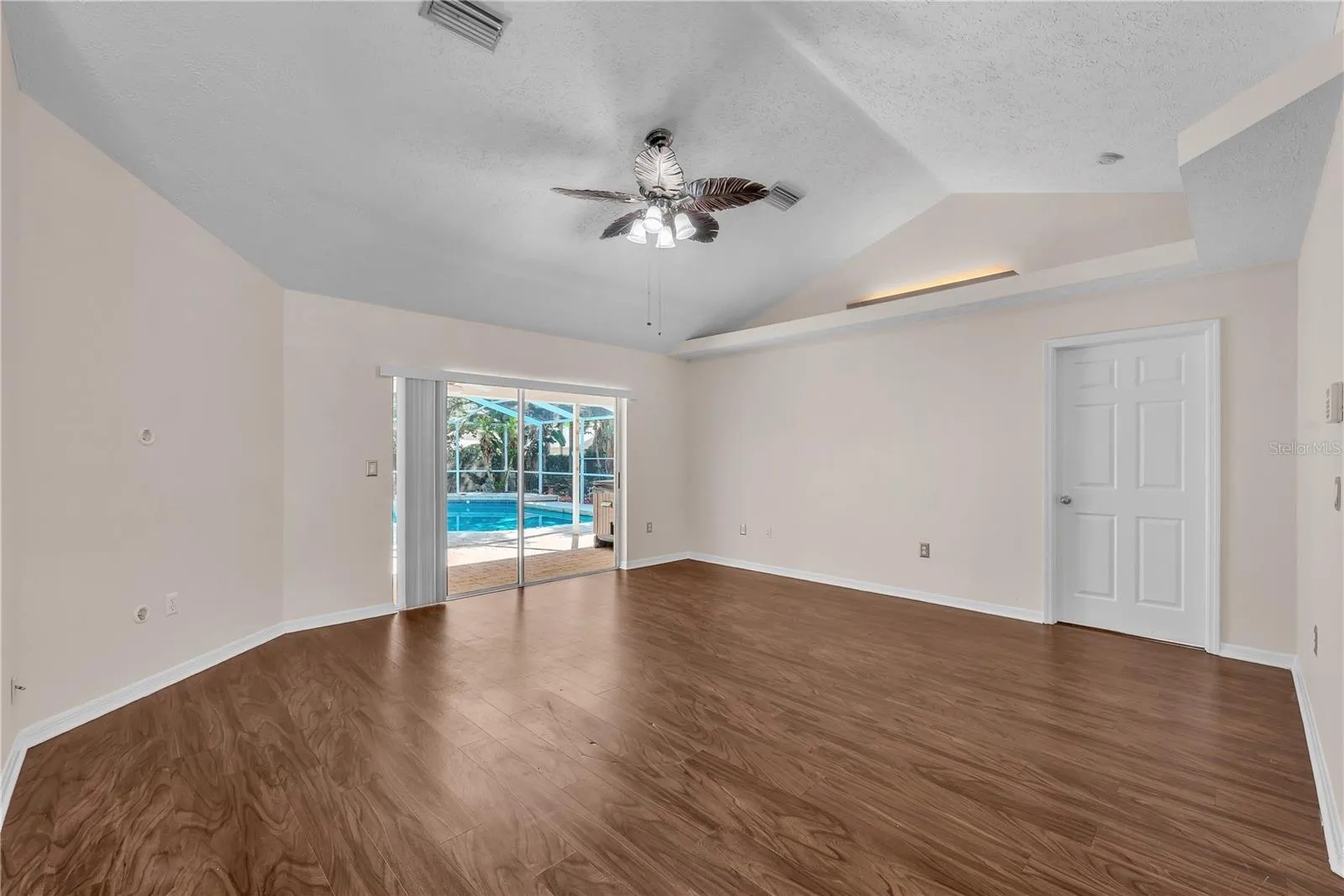 As you enter the living room, your eye is naturally drawn through the space to the sparkling pool and inviting backyard beyond, creating an immediate sense of openness and Florida-style indoor-outdoor living.