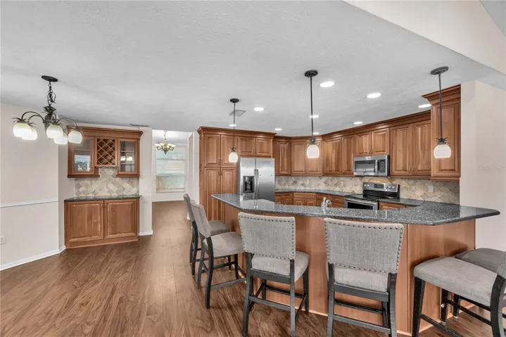 The breakfast bar provides additional seating, while a wall of cabinetry with a built-in wine rack and glass-front doors offers the perfect spot for displaying serving pieces and setting out appetizers for guests or creating a convenient coffee station.
