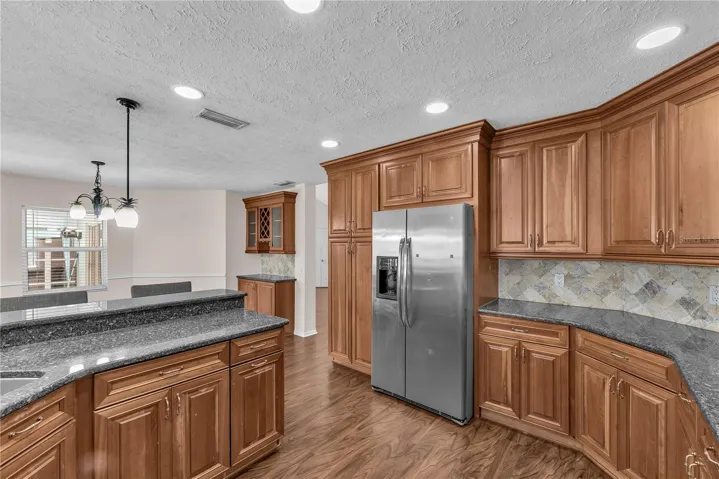 At the heart of the home, the spacious kitchen features custom wood cabinetry, Level 5 granite countertops, stone backsplash and stainless steel appliances.