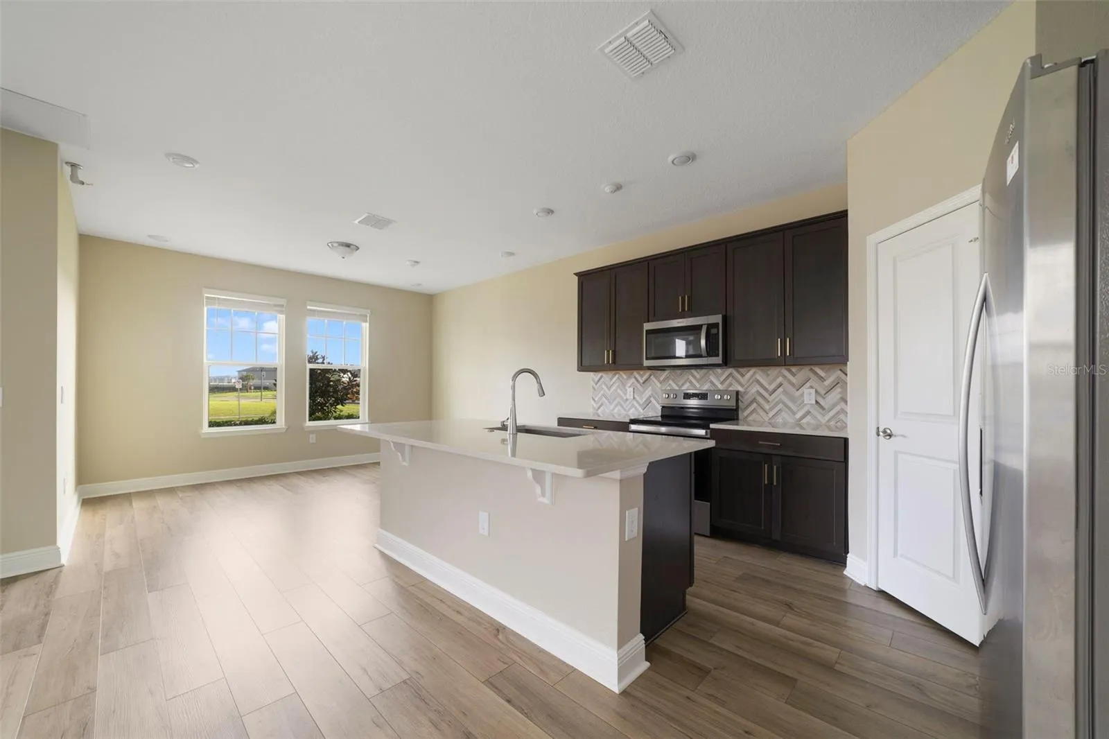 The Kitchen is designed for both everyday living and entertaining, featuring STAINLESS STEEL APPLIANCES, QUARTZ COUNTERTOPS, a SLEEK BACKSPLASH, a spacious island with BREAKFAST BAR SEATING and a convenient WALK-IN PANTRY CLOSET.