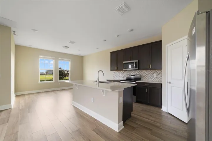 The Kitchen is designed for both everyday living and entertaining, featuring STAINLESS STEEL APPLIANCES, QUARTZ COUNTERTOPS, a SLEEK BACKSPLASH, a spacious island with BREAKFAST BAR SEATING and a convenient WALK-IN PANTRY CLOSET.