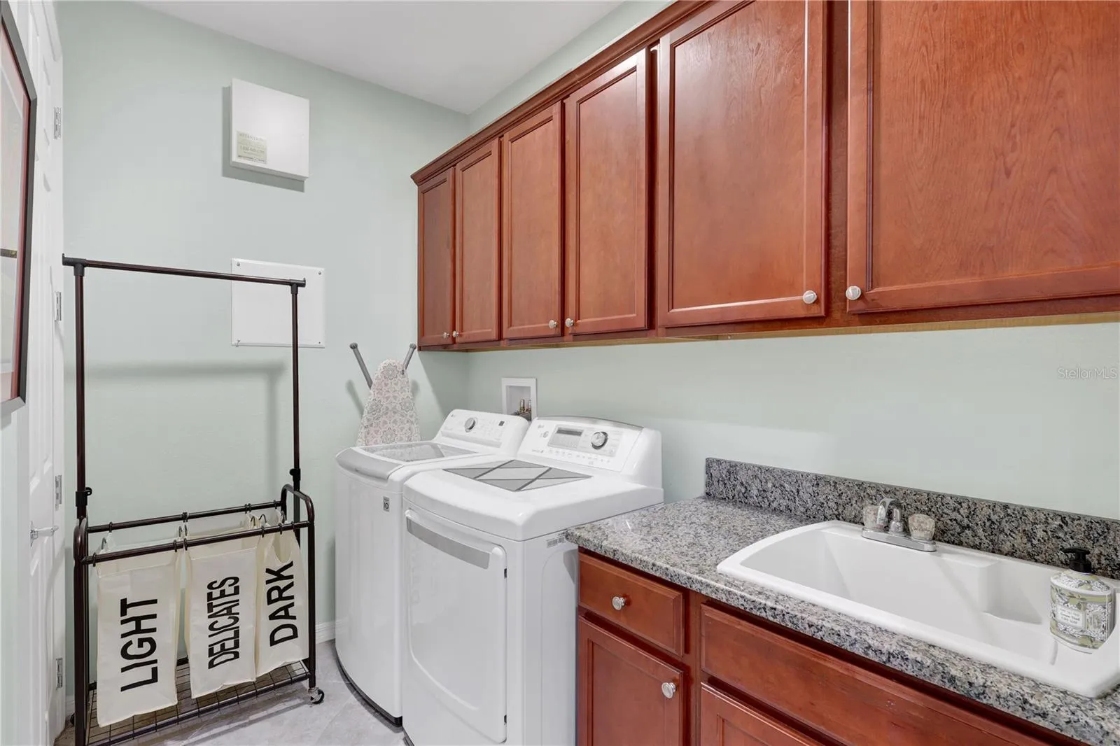 INSIDE LAUNDRY ROOM WITH UTILITY SINK AND CABINETS