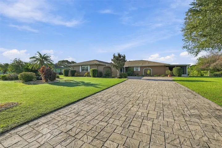 Beautiful manicured landscaping and custom pavered driveway, which is long and wide for multiple vehicles.