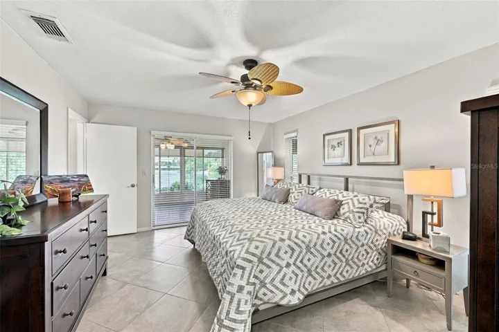 Primary bedroom is large, bright and relacing.  Notice the consistent flooring throughout the home. Large beautiful sliding glass doors allow natural Florida sunshine to filter into the room with a view of the water.