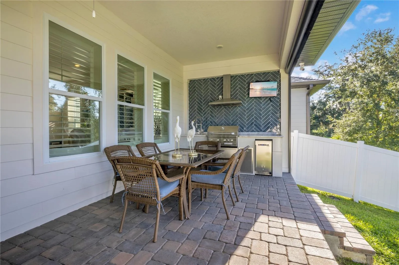 Covered outdoor dining area with a custom summer kitchen, built-in grill and beverage refrigerator.