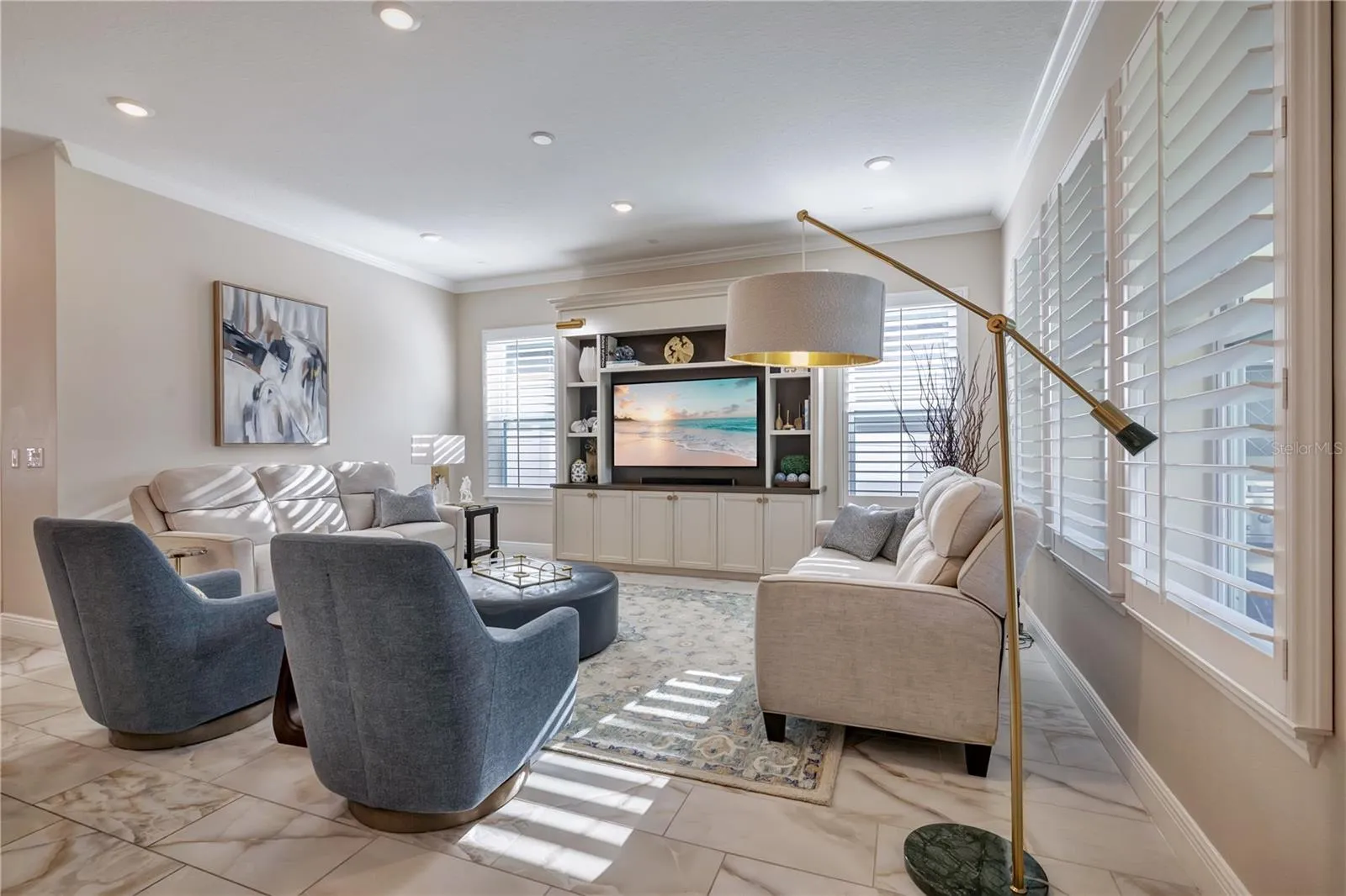 Inviting family room featuring crown molding, recessed lighting and plantation shutters.
