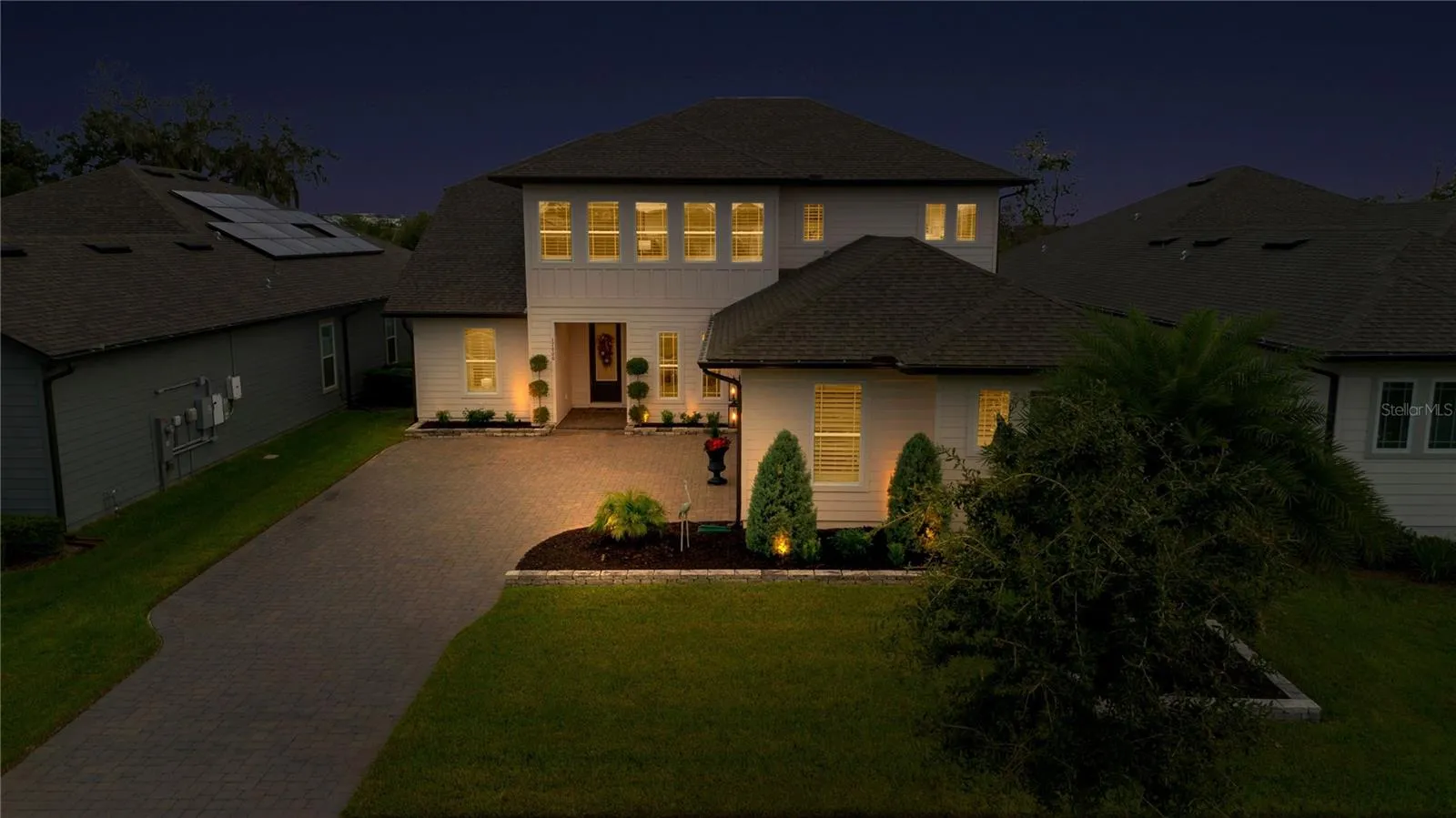 Elevated evening view highlights the front entrance, driveway and landscape lighting.