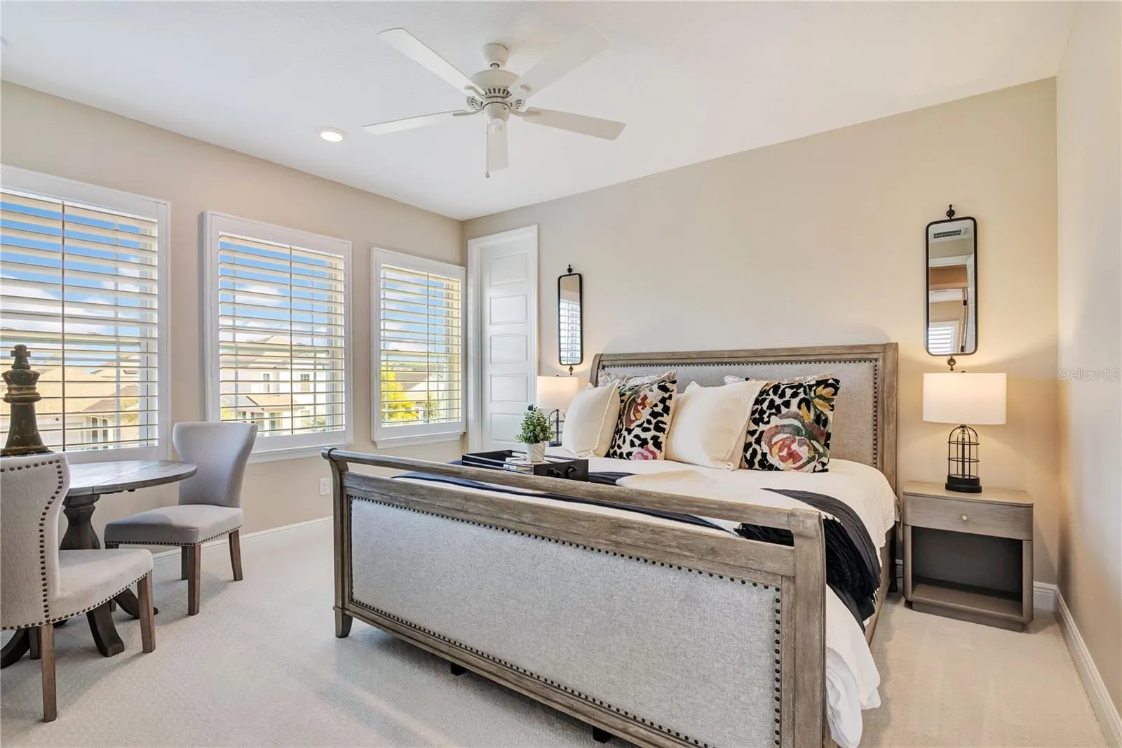 Inviting bedroom featuring plush carpet, plantation shutters and a ceiling fan.