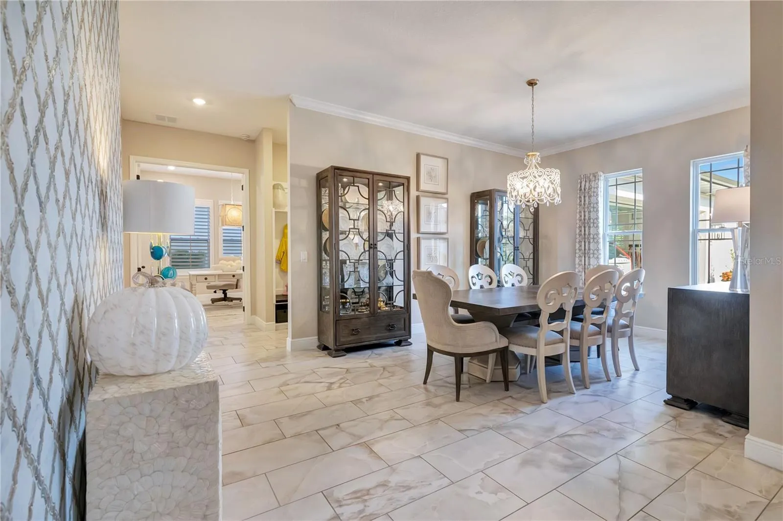 Elegant dining room featuring a statement chandelier, crown molding and upgraded tile flooring.