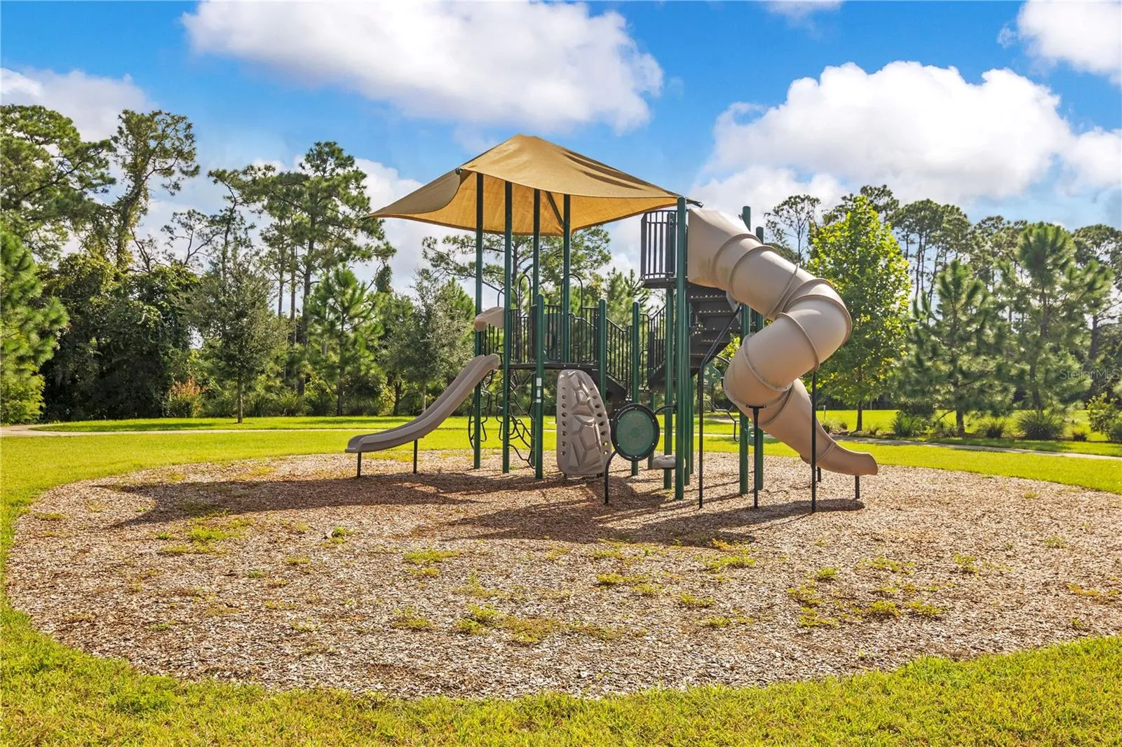 Community playground featuring climbing structures and slides in an open grassy setting.