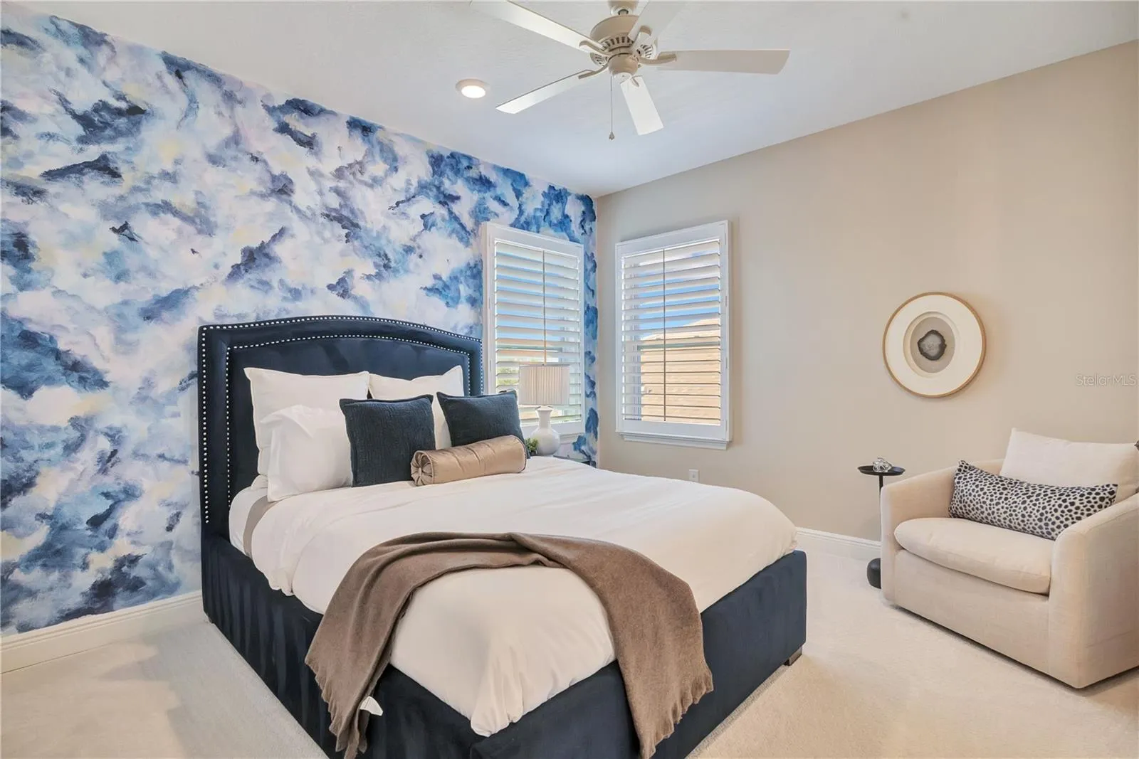 Bedroom featuring a blue statement accent wall, plush carpet and space for a reading chair.