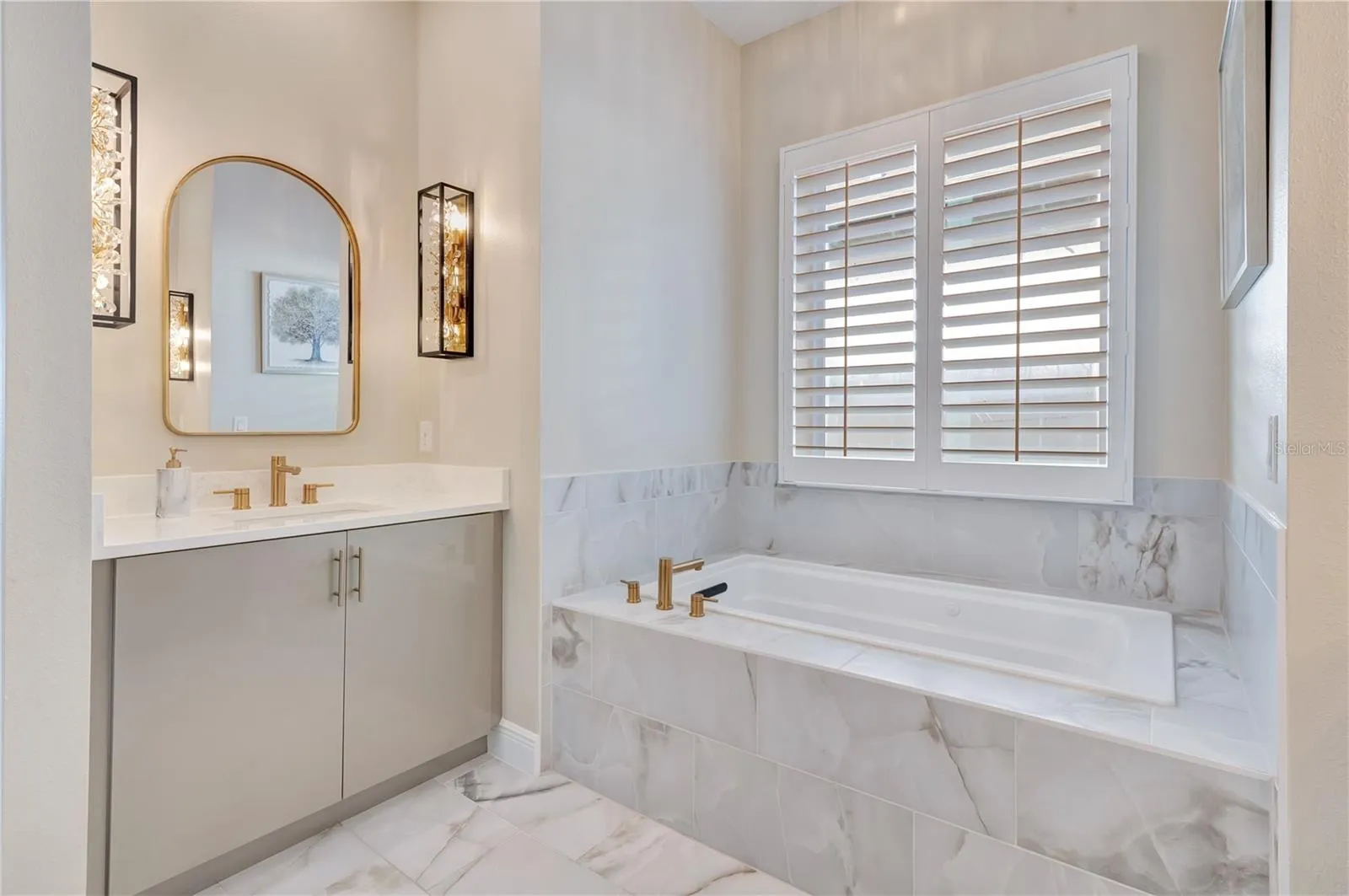 Elegant bathroom featuring a soaking tub, upgraded tile surrounds and a vanity accented by designer sconces.