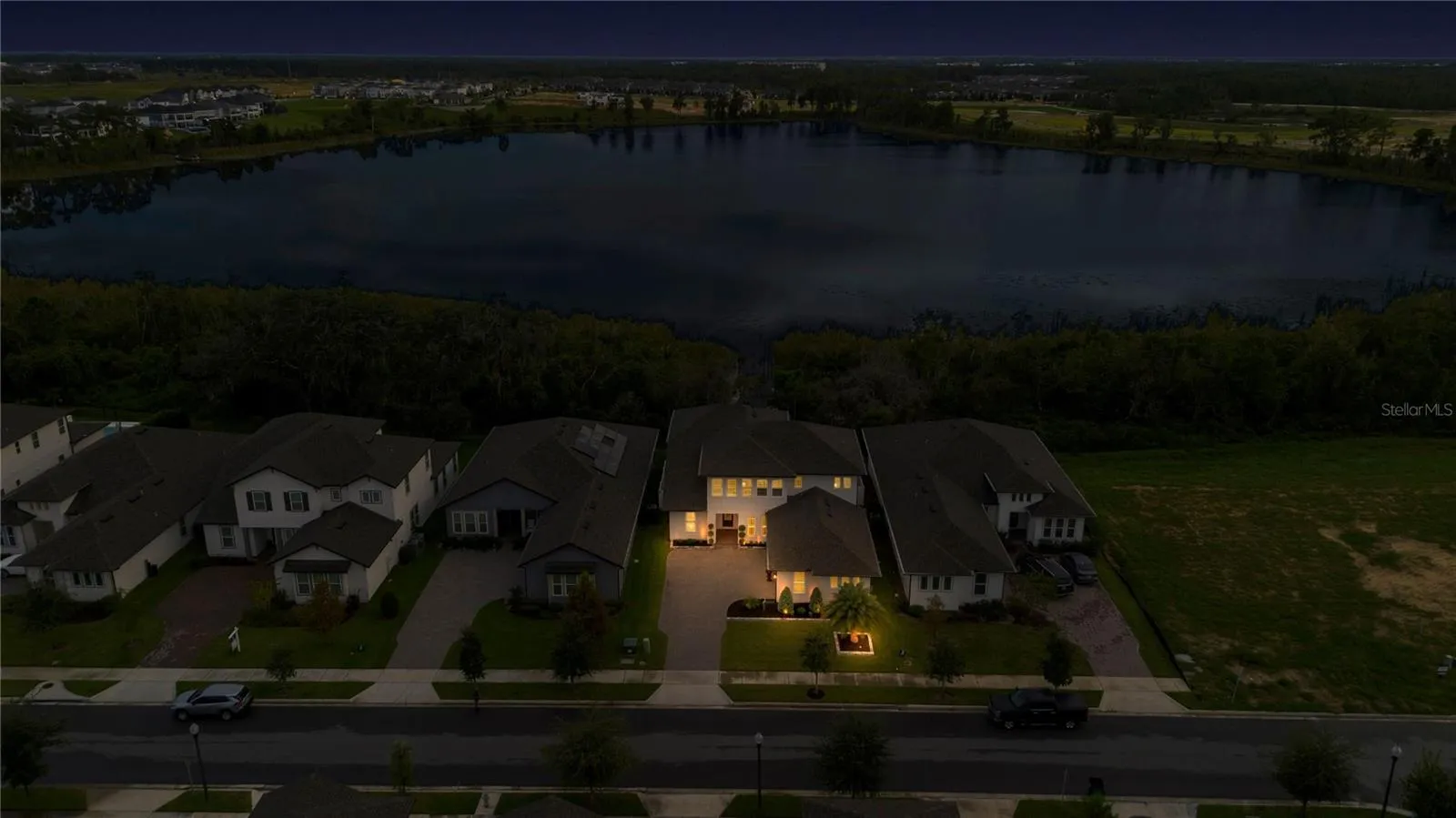 Wide twilight aerial captures the property, neighboring homes and lake setting.