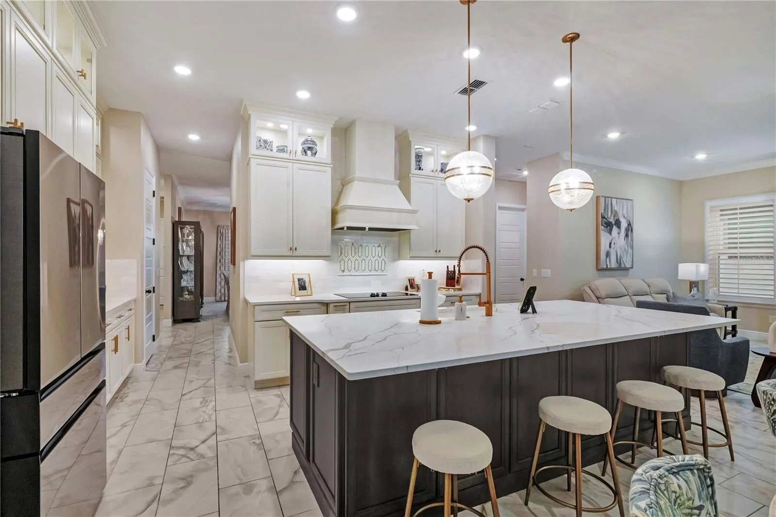 Upgraded kitchen featuring an oversized island with seating, contrasting cabinetry and designer pendant lighting.